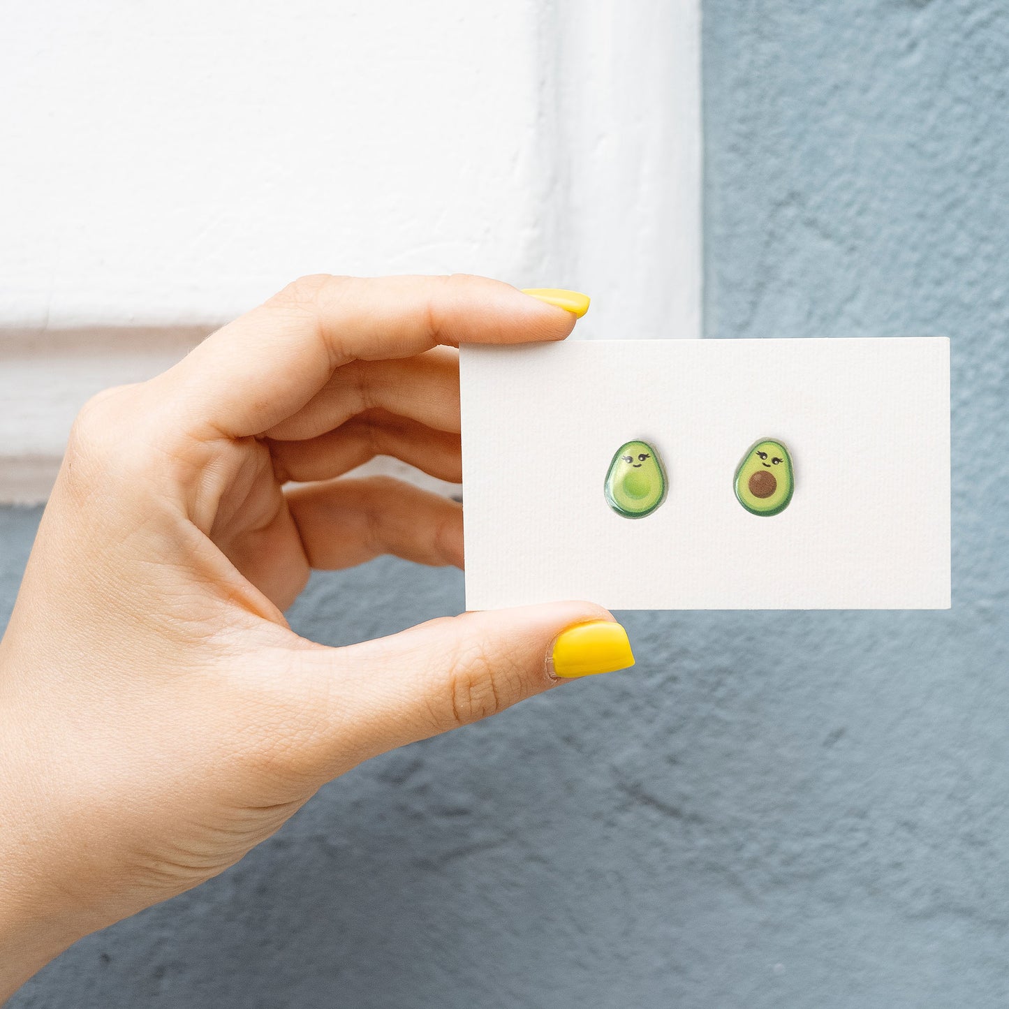 woman holding cute avocado earrings